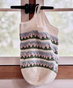 A crochet market bag hanging in a window