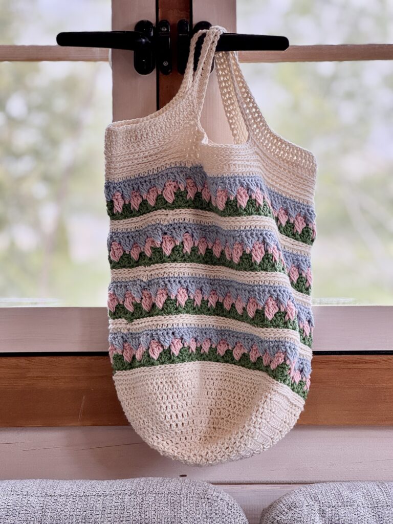 A Crochet Market Bag hanging in a window