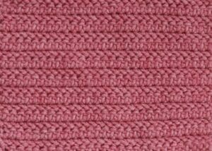 A swatch of the herringbone half double crochet stitch worked in a pink yarn