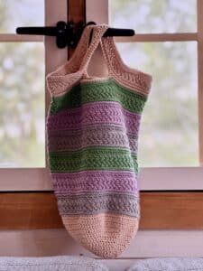 The crochet Market Day Market Bag hanging from a window