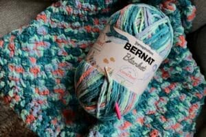a ball of Bernat Blanket Colour of the Year laying over top the Coral Reef Blanket