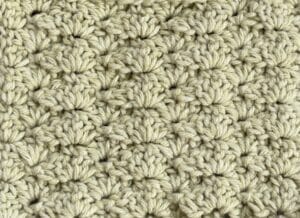 A swatch of the closed shell crochet stitch pattern worked in a light green yarn
