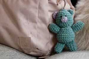 a teddy bear keychain hanging on a backpack
